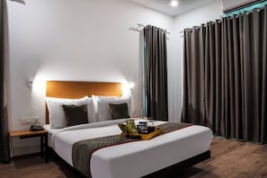 A hotel room with a bed, bedside table, and a nightstand.