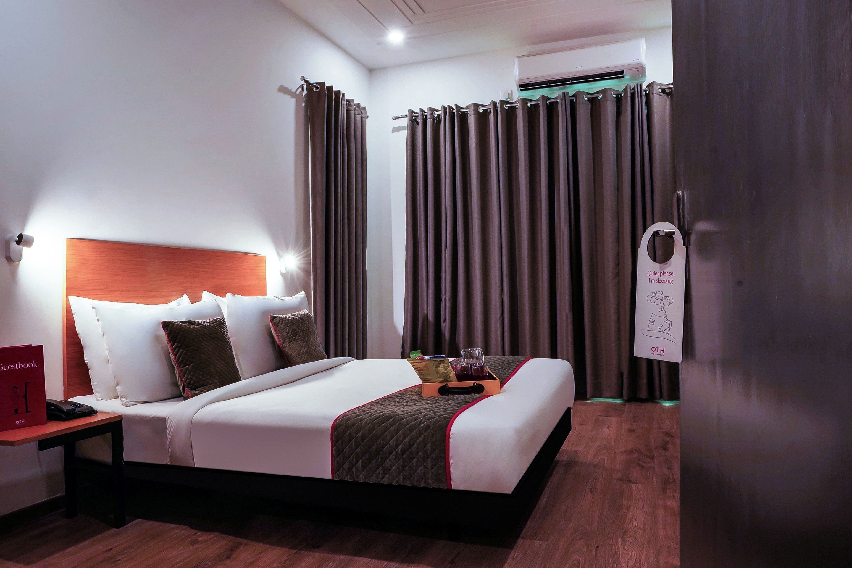 A hotel room with a bed, bedside table, and a nightstand with a telephone.