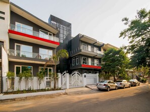 A multi-story building with balconies, a gated entrance, and parked cars. - Townhouse Galleria Market Near  (Gurugram)