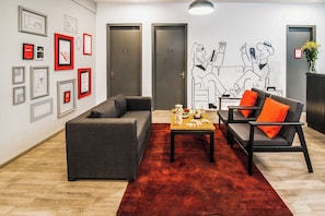 A modern lounge area with grey sofas, a red carpet, and artwork on the walls. - Townhouse Galleria Market Near  (Gurugram)