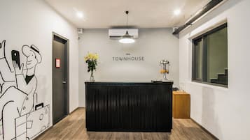 A reception desk with a 'Townhouse' sign, a wall-mounted air conditioner, and a window with a view.