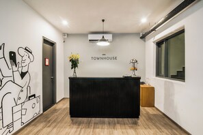 A reception desk with a 'Townhouse' sign, a wall-mounted air conditioner, and a window with a view.