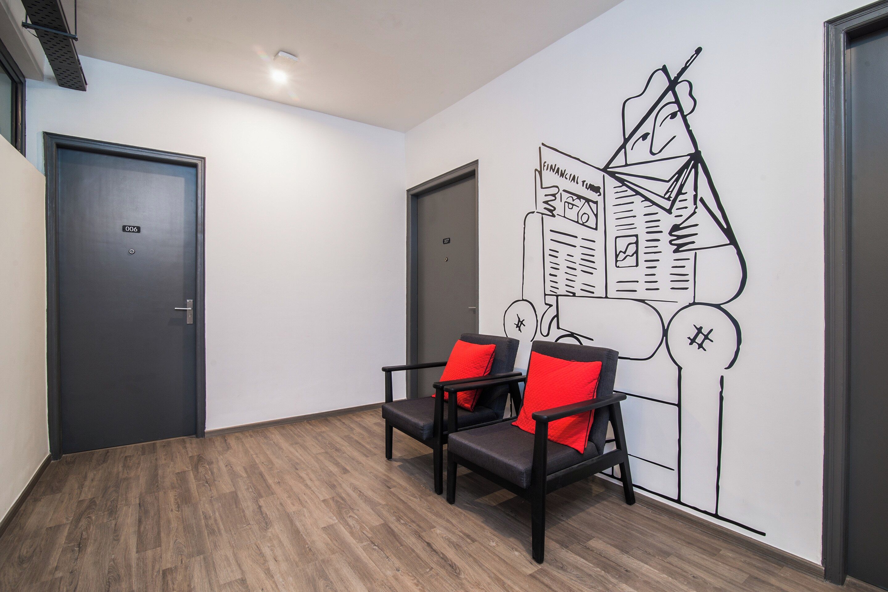 A hallway with two doors, a wall mural, and two chairs with red cushions.