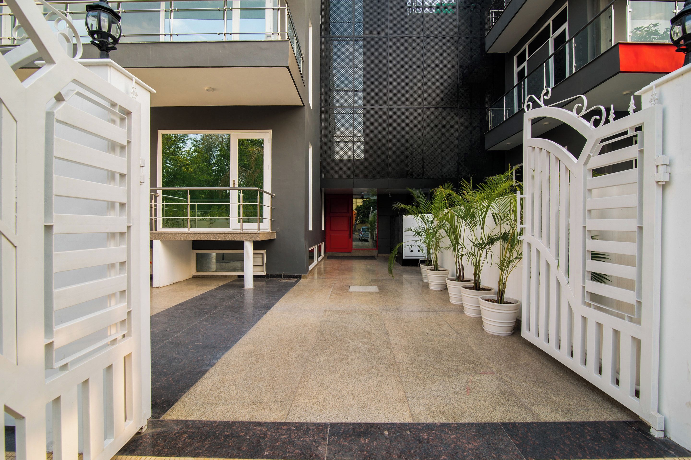 A modern building with a covered walkway, potted plants, and a gated entrance.