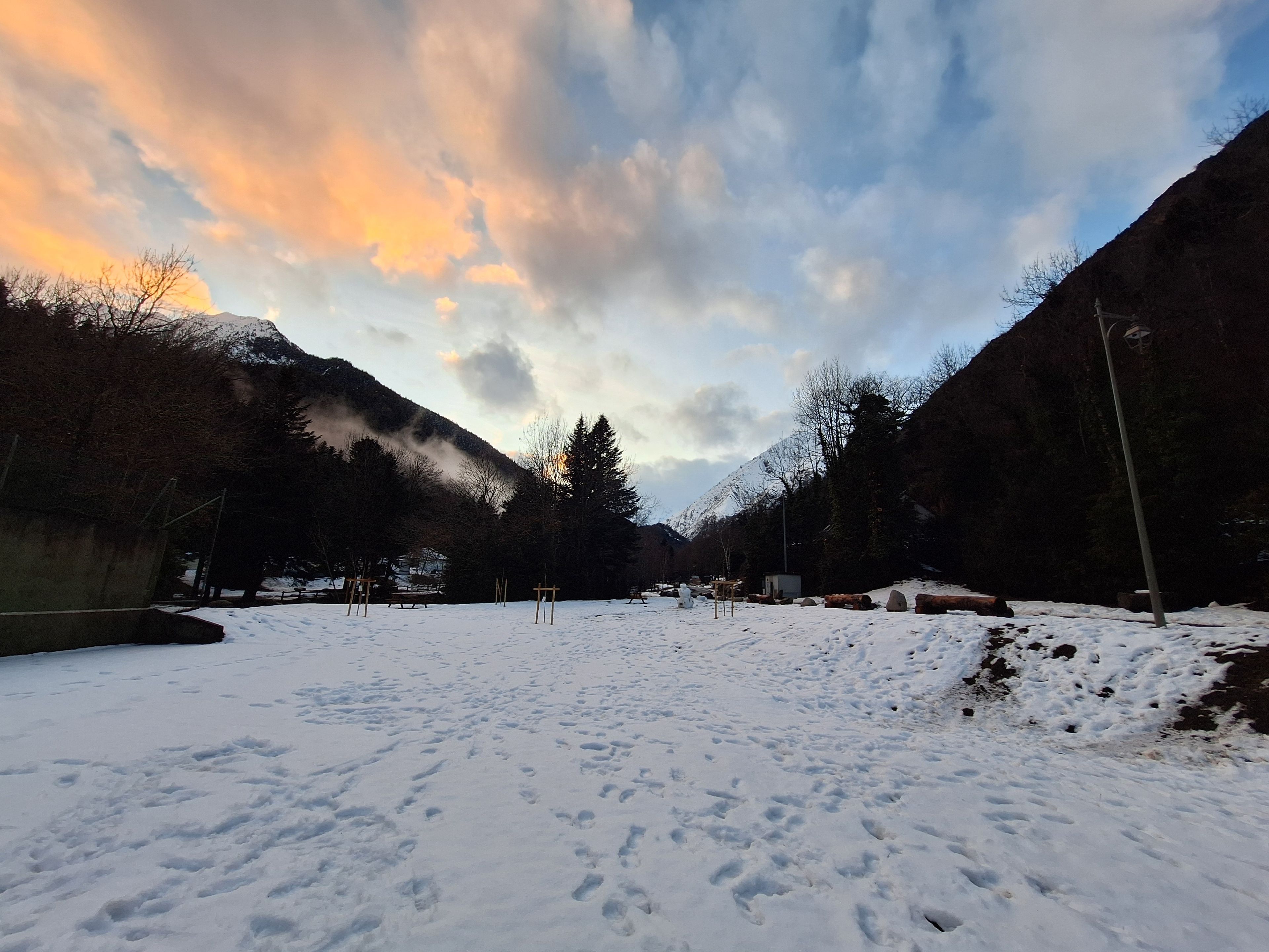 Et sneklædt landskab med bjerge i baggrunden og en klar himmel.