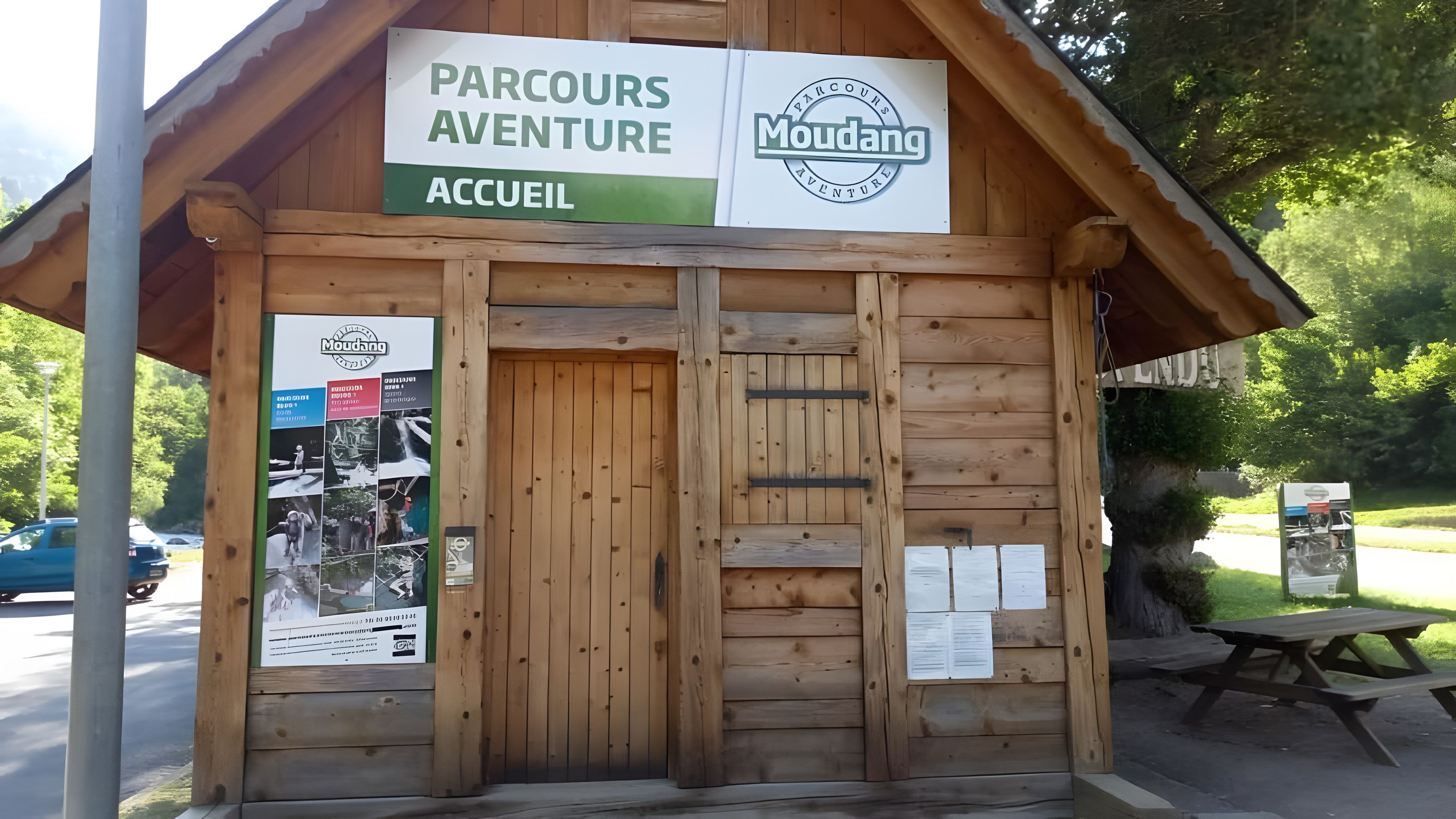 A wooden building labeled 'Parcours Aventure Accueil' with a signboard and a poster on the left.