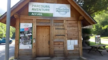 A wooden building labeled 'Parcours Aventure Accueil' with a signboard and a poster on the left.