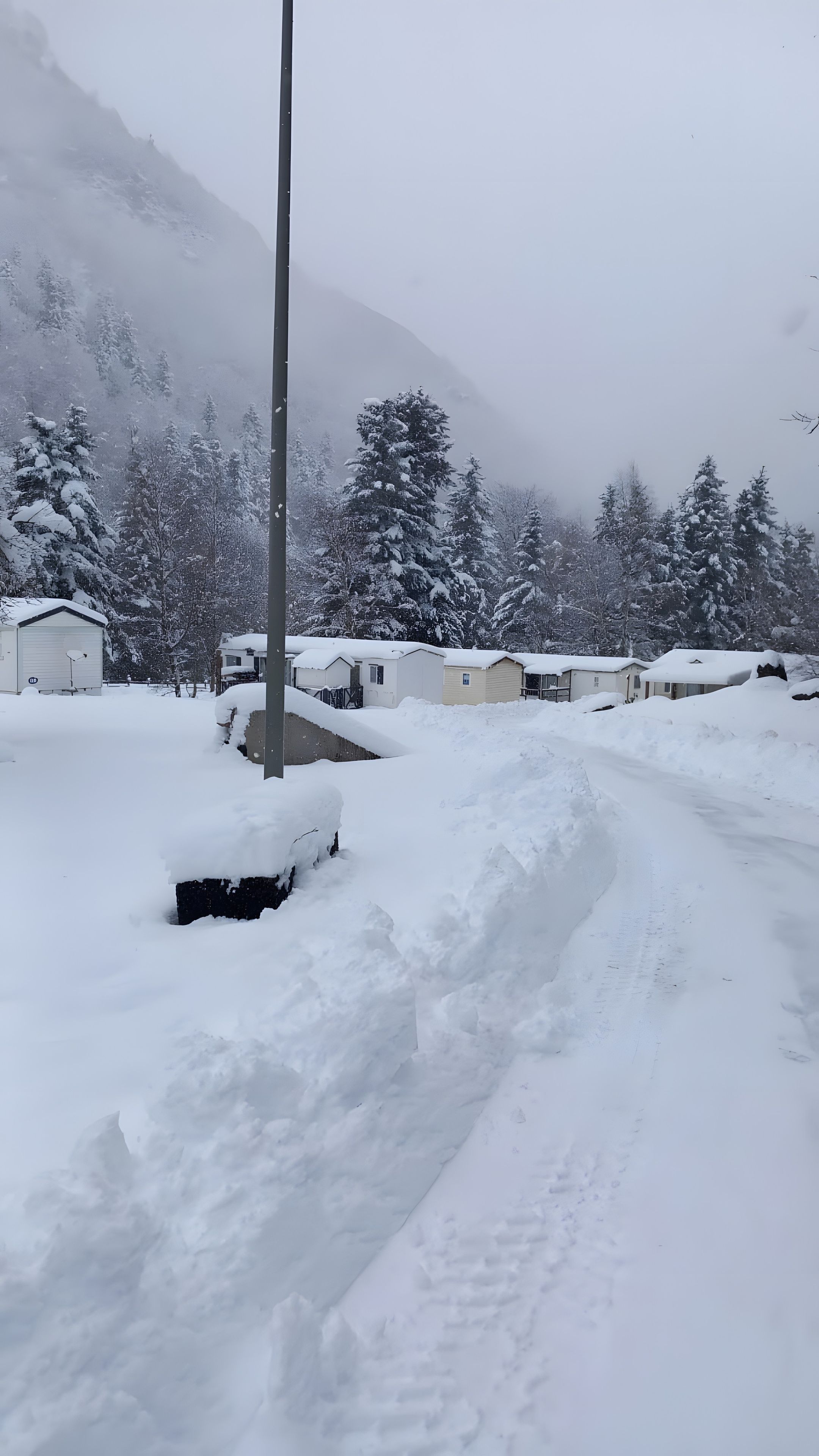 Ein schneebedecktes Wohngebiet mit Häusern und einem Berg im Hintergrund.