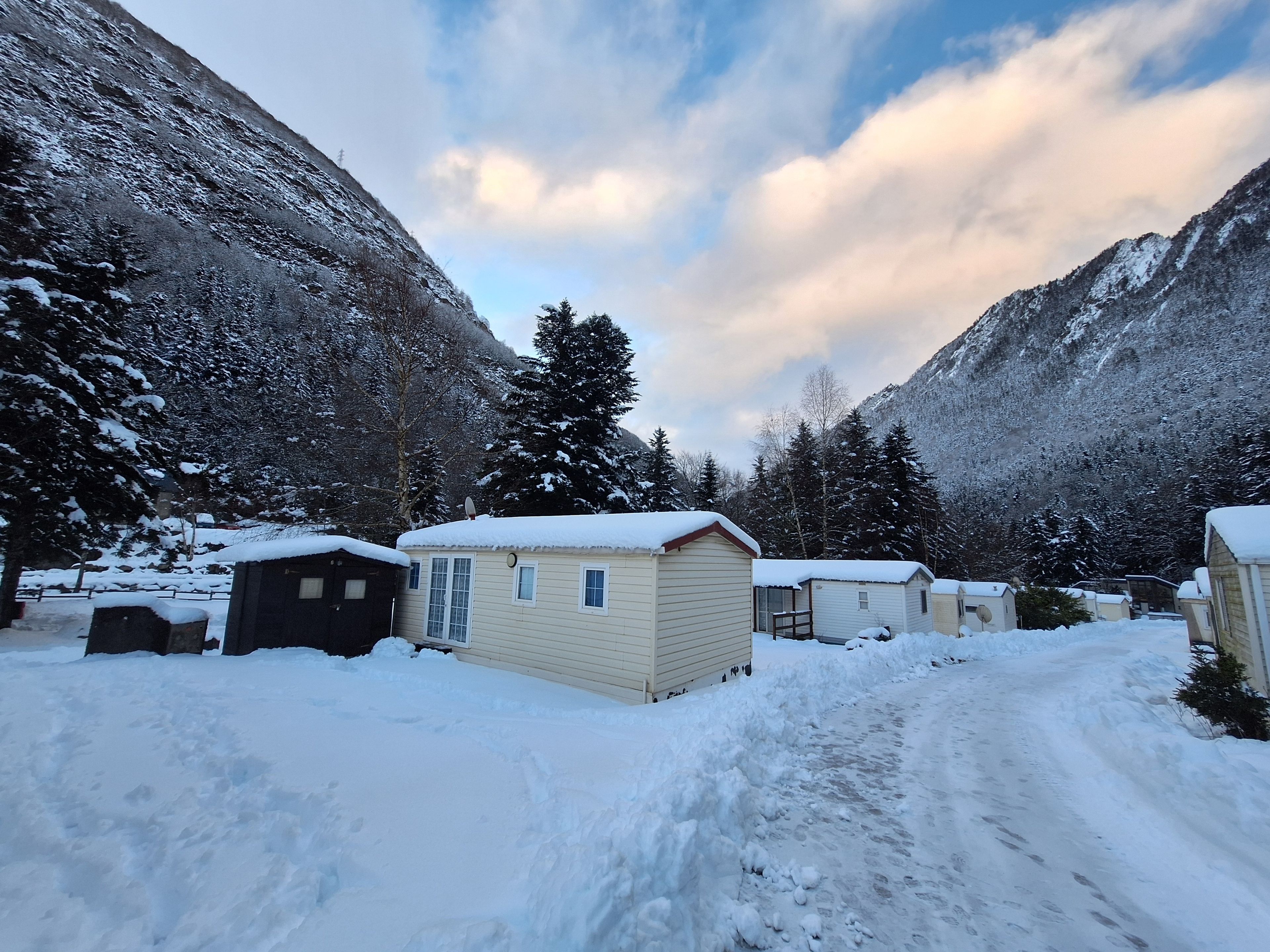 Un espacio exterior cubierto de nieve con cabañas y una montaña al fondo.