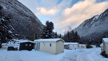 Un espacio exterior cubierto de nieve con cabañas y una montaña al fondo.