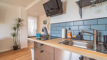 A modern kitchen with a built-in dishwasher, a coffee machine, and a stainless steel sink.