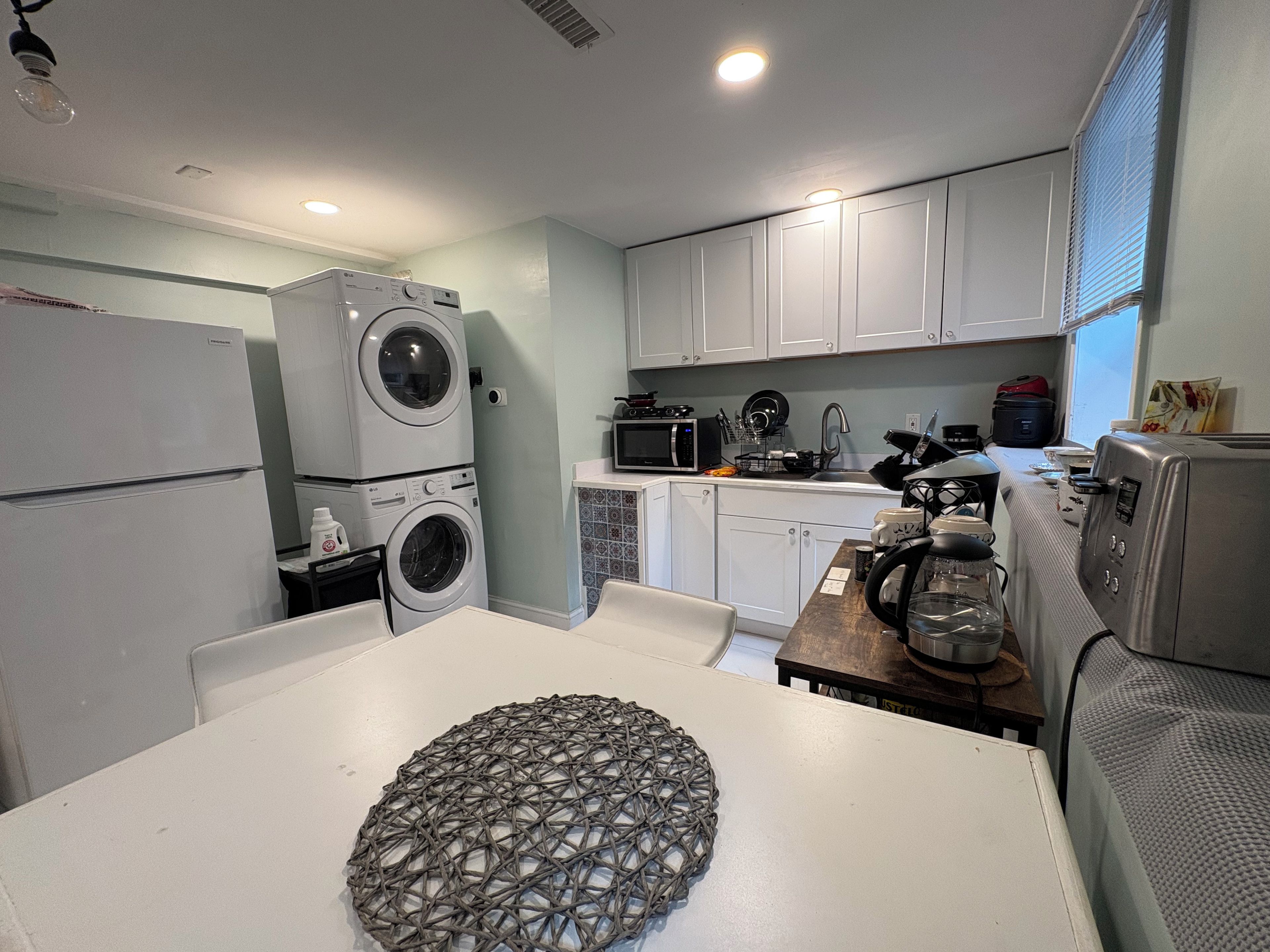 Een kleine keuken met een wasmachine, magnetron en broodrooster.