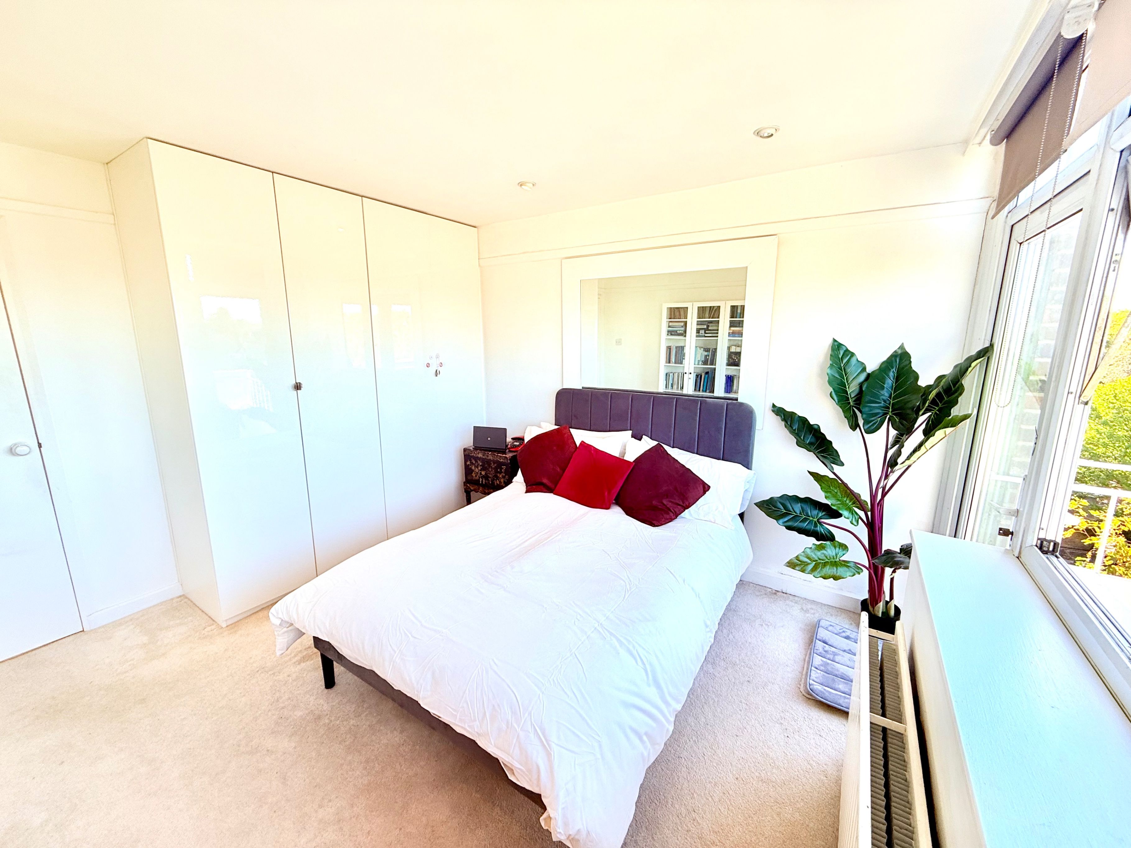 A bedroom with a bed, wardrobe, bedside table, and a window with a view.
