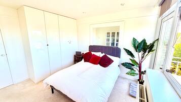 A bedroom with a bed, wardrobe, bedside table, and a window with a view.