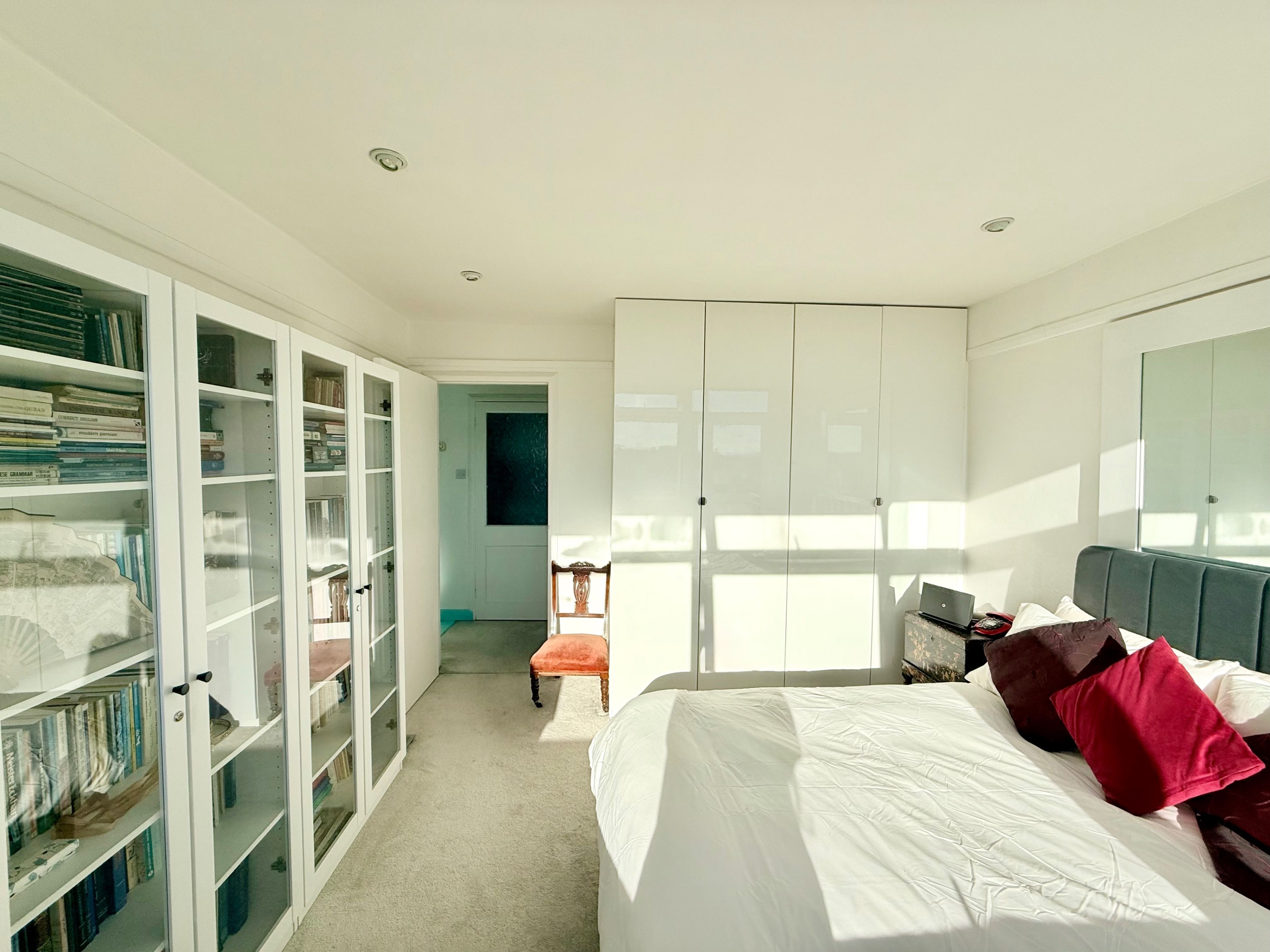 Un dormitorio con cama, armario y estantería.