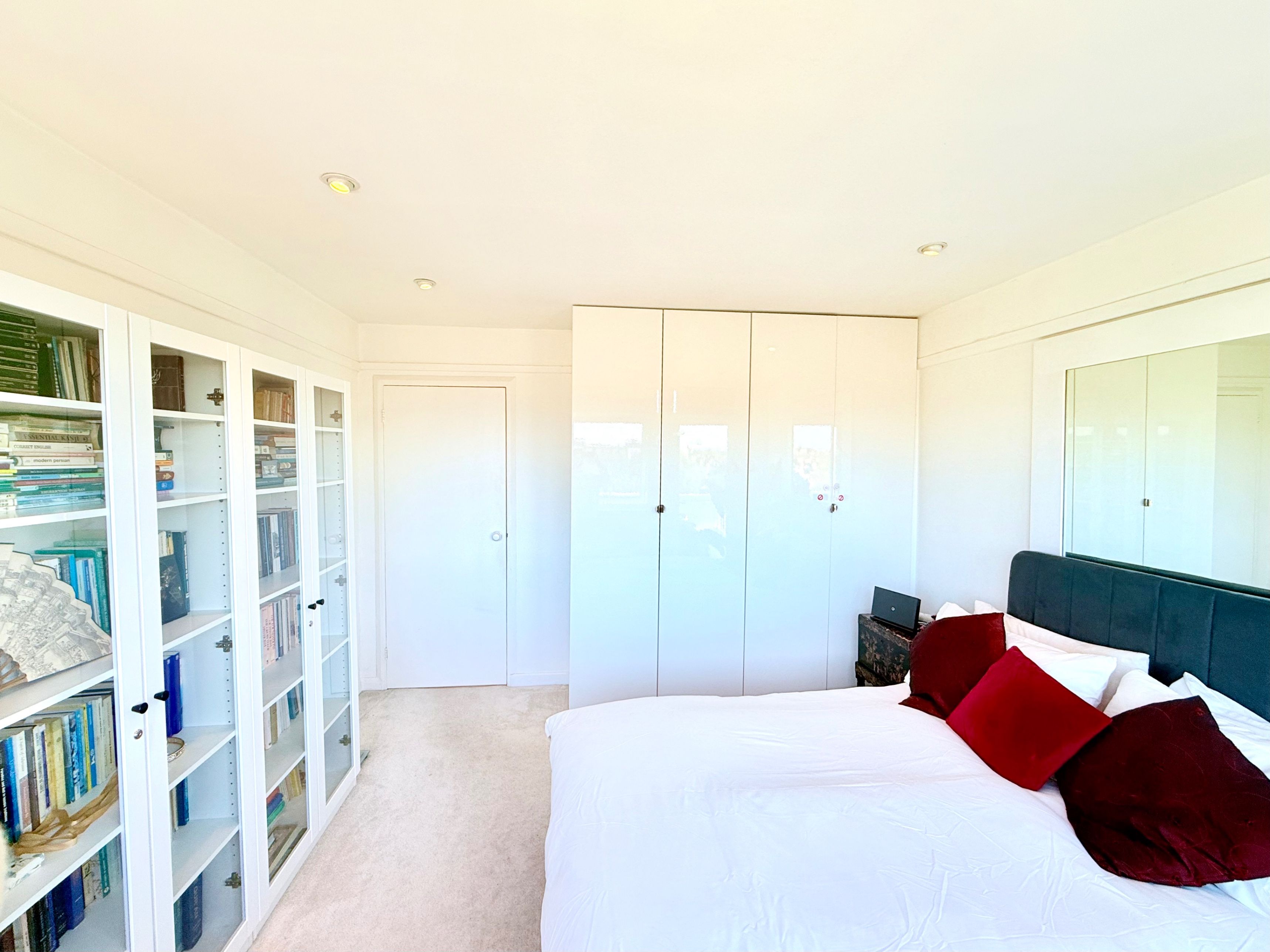A bedroom with a bed, a wardrobe, and a bookshelf.