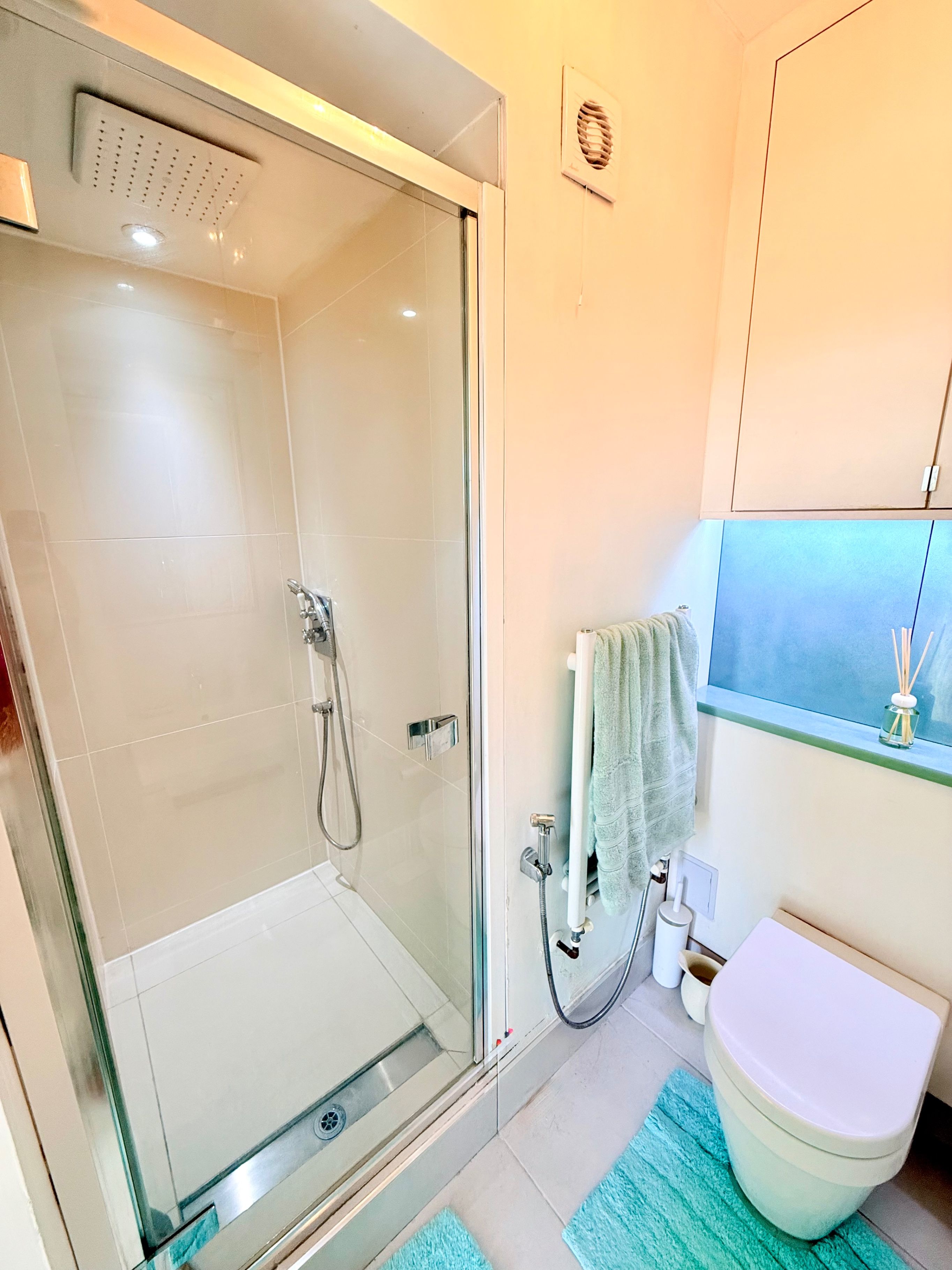 A bathroom with a glass-enclosed shower, a toilet, and a sink.