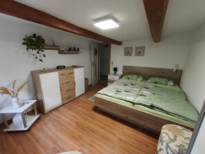A bedroom with a wooden bed, a desk, a wardrobe, a nightstand, and a wall-mounted shelf with decorative items. - Apartment 'Berndt-Mühle' with Mountain View, Shared Terrace and Wi-Fi (Oderwitz)