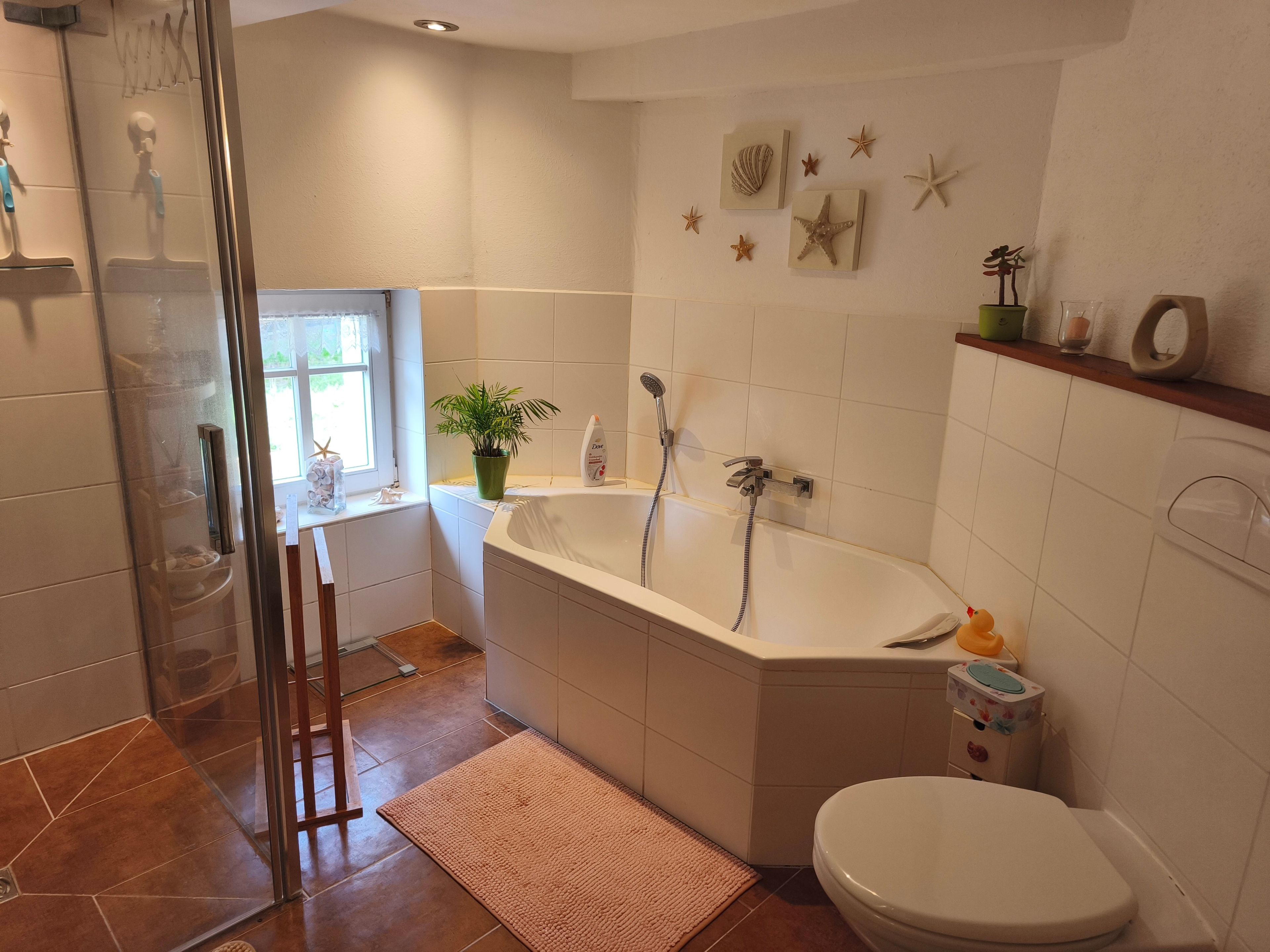 Une salle de bain avec une baignoire, des toilettes, une douche et une fenêtre.