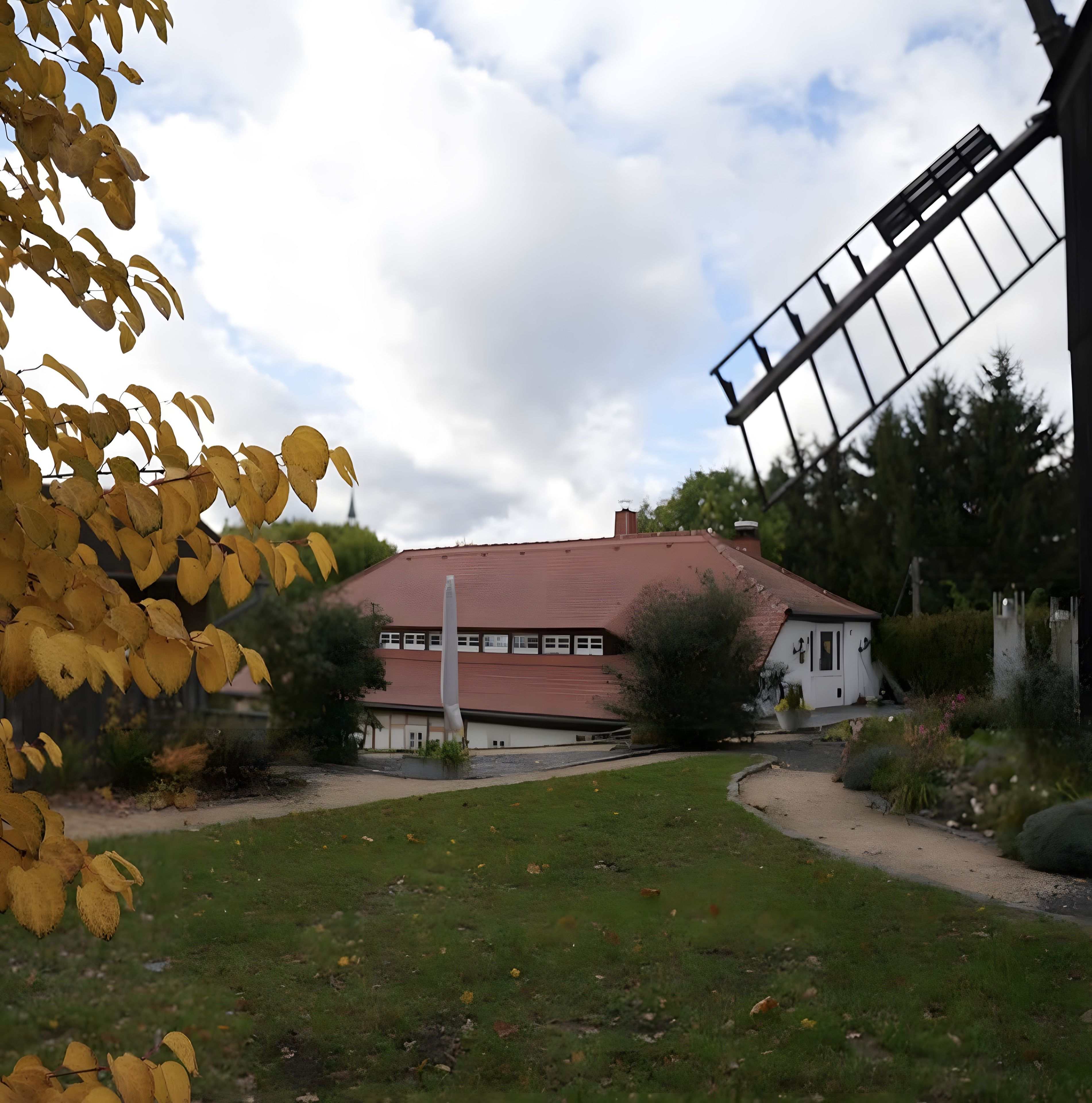 A building with a red roof, surrounded by a grassy area and trees.