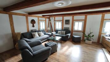 Ein Wohnzimmer mit Sofa, Sesseln, Hocker und Couchtisch.