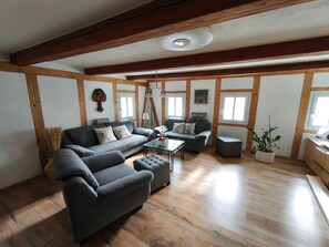 A living room with a sofa, armchair, ottoman, and a coffee table. - Apartment 'Berndt-Mühle' with Mountain View, Shared Terrace and Wi-Fi (Oderwitz)