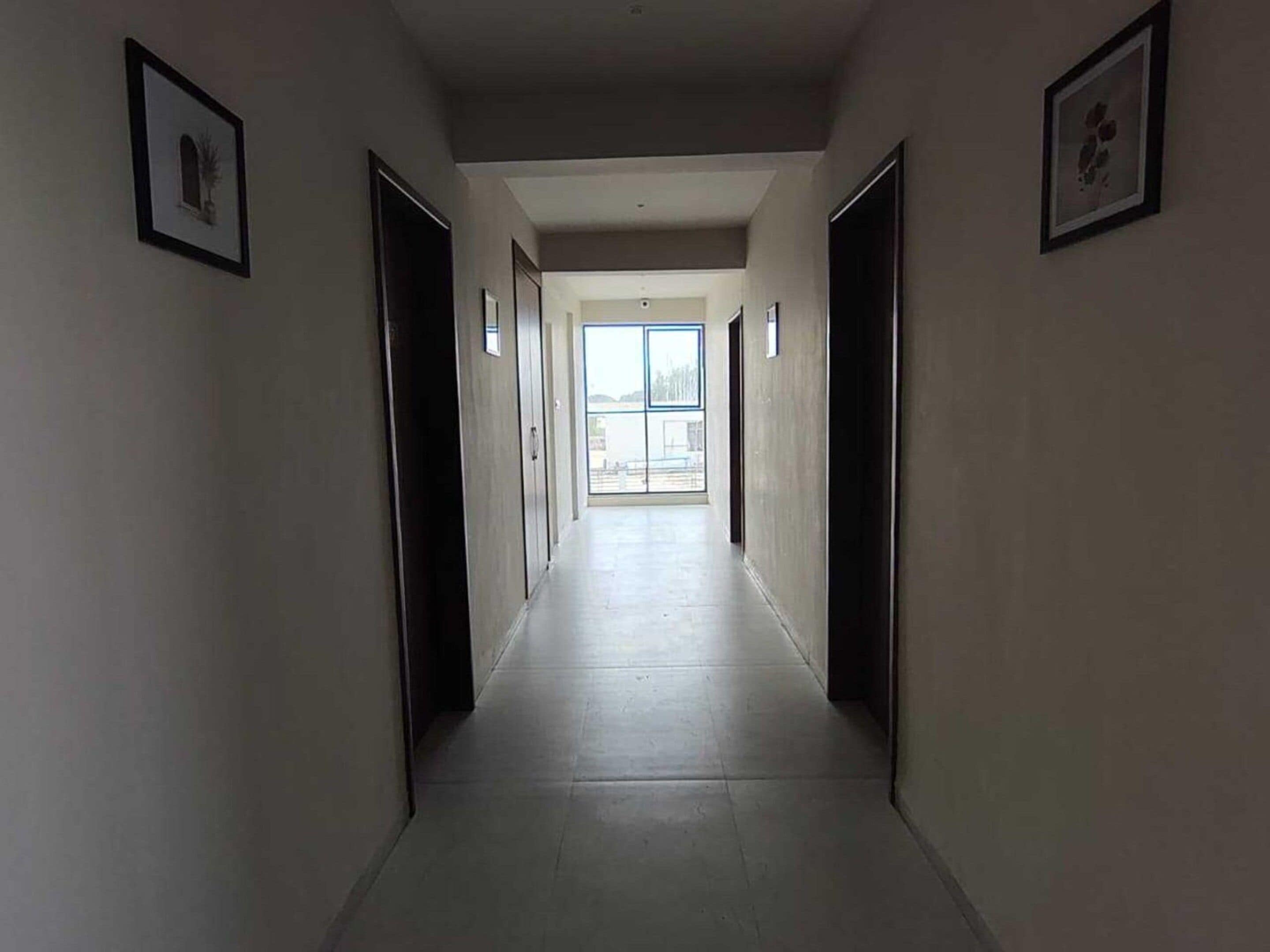 A long, narrow hallway with doors on both sides leading to rooms.