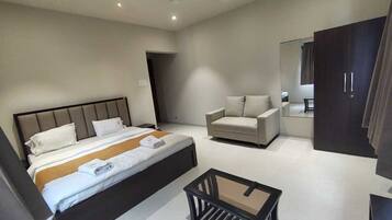 A modern hotel room with a bed, a sofa, a small table, and a wardrobe.