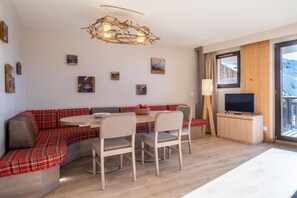 A modern living room with a red plaid sofa, a dining table with chairs, a flat-screen TV, and a large window with a view of a snowy landscape. - 10m from ski slopes, balcony, ski locker, 52-62m², Avoriaz (Avoriaz)
