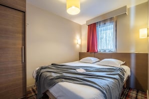 A hotel room with a bed, a wardrobe, a window with curtains, and wall-mounted lights. - 10m from ski slopes, balcony, ski locker, 52-62m², Avoriaz (Avoriaz)