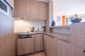 Eine moderne Küche mit Holzschränken, einem eingebauten Geschirrspüler und einer Spüle aus Edelstahl.