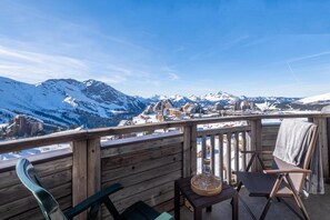 Eine Holterrasse mit Blick auf schneebedeckte Berge und eine darunter liegende Stadt.