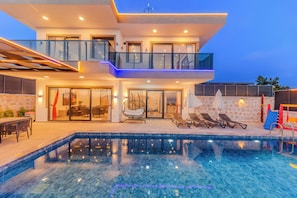 A modern two-story house with a swimming pool, glass railings, and outdoor furniture. - zeytintepe villa (Antalya)