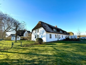 A white building with a thatched roof, surrounded by a well-maintained lawn and a fence. - 3 in the Deichhof House (Dunsum)