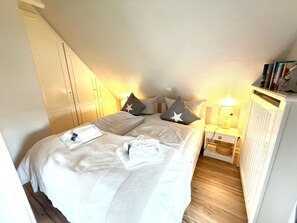 A bedroom with a bed, pillows, a bedside table, a lamp, and a radiator. - 3 in the Deichhof House (Dunsum)