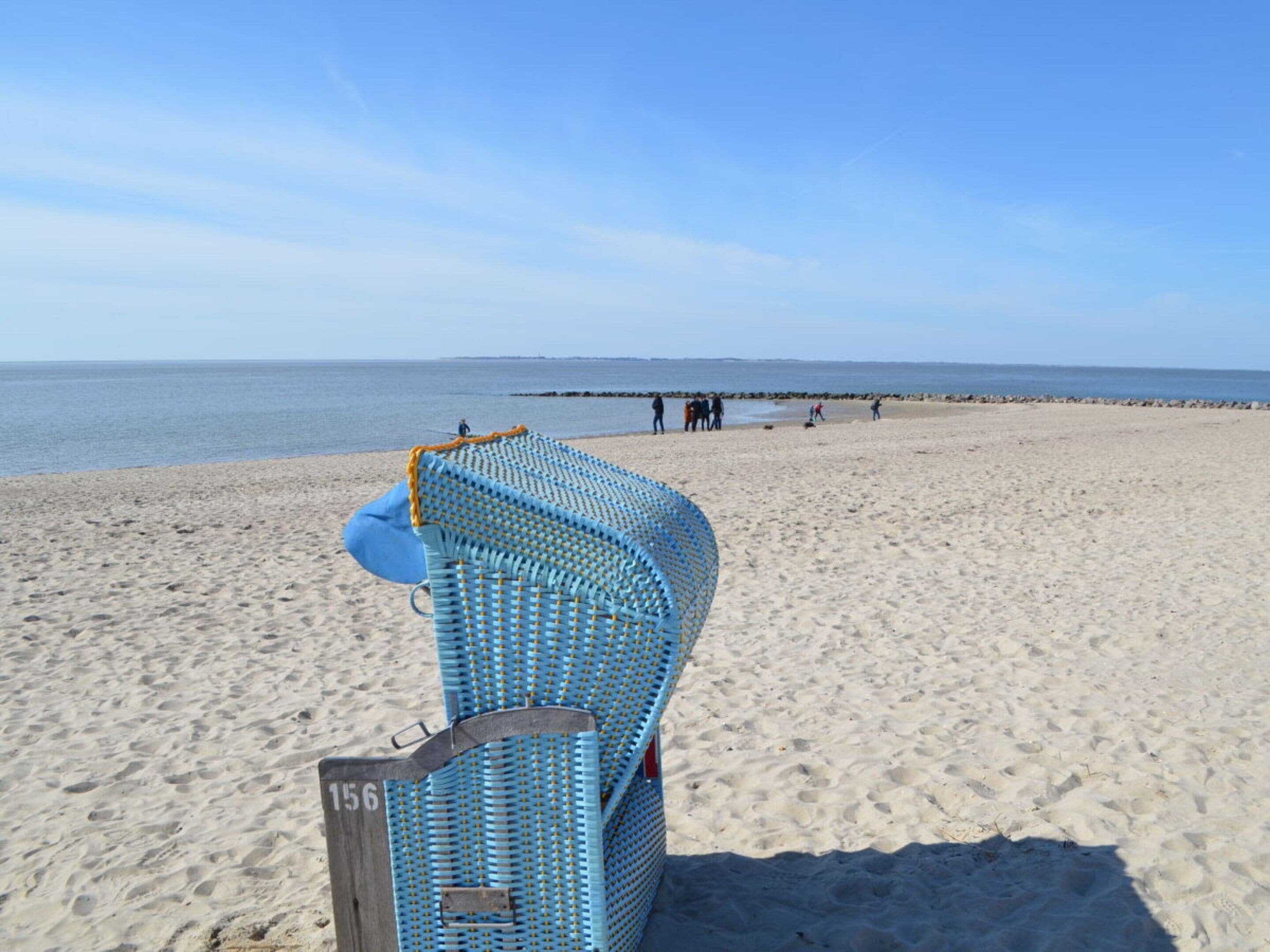 A beach with a blue chair and a numbered sign, indicating a designated area.