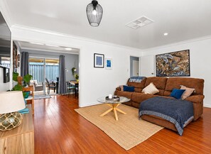 Ein modernes Wohnzimmer mit einem braunen Sofa, einem Couchtisch und einem Essbereich mit Tisch und Stühlen.