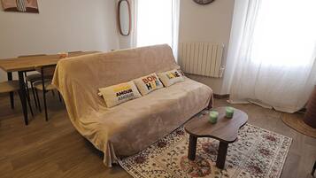 Ein Wohnzimmer mit einer Couch, einem Couchtisch, einem Esstisch und einer Wanduhr.