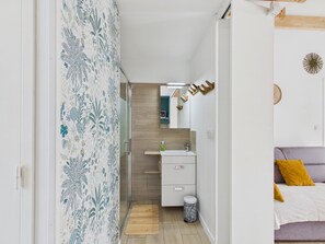 A narrow hallway leading to a bathroom with a sink, mirror, and wooden flooring. - Studio for 4, heated pool & shared garden (Saint-Alban)