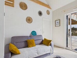 Ett rum med en grå soffa, två gula kuddar, en vit pläd och en blå, rund skylt på väggen.