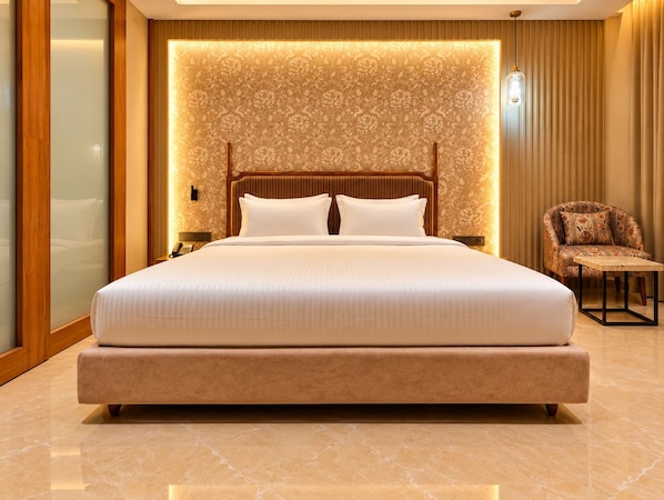 A large bed with a headboard, a bedside table, and a chair.