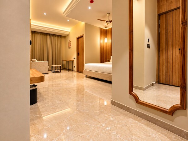 A hotel room with a bed, a ceiling fan, a wooden door, and a large mirror.