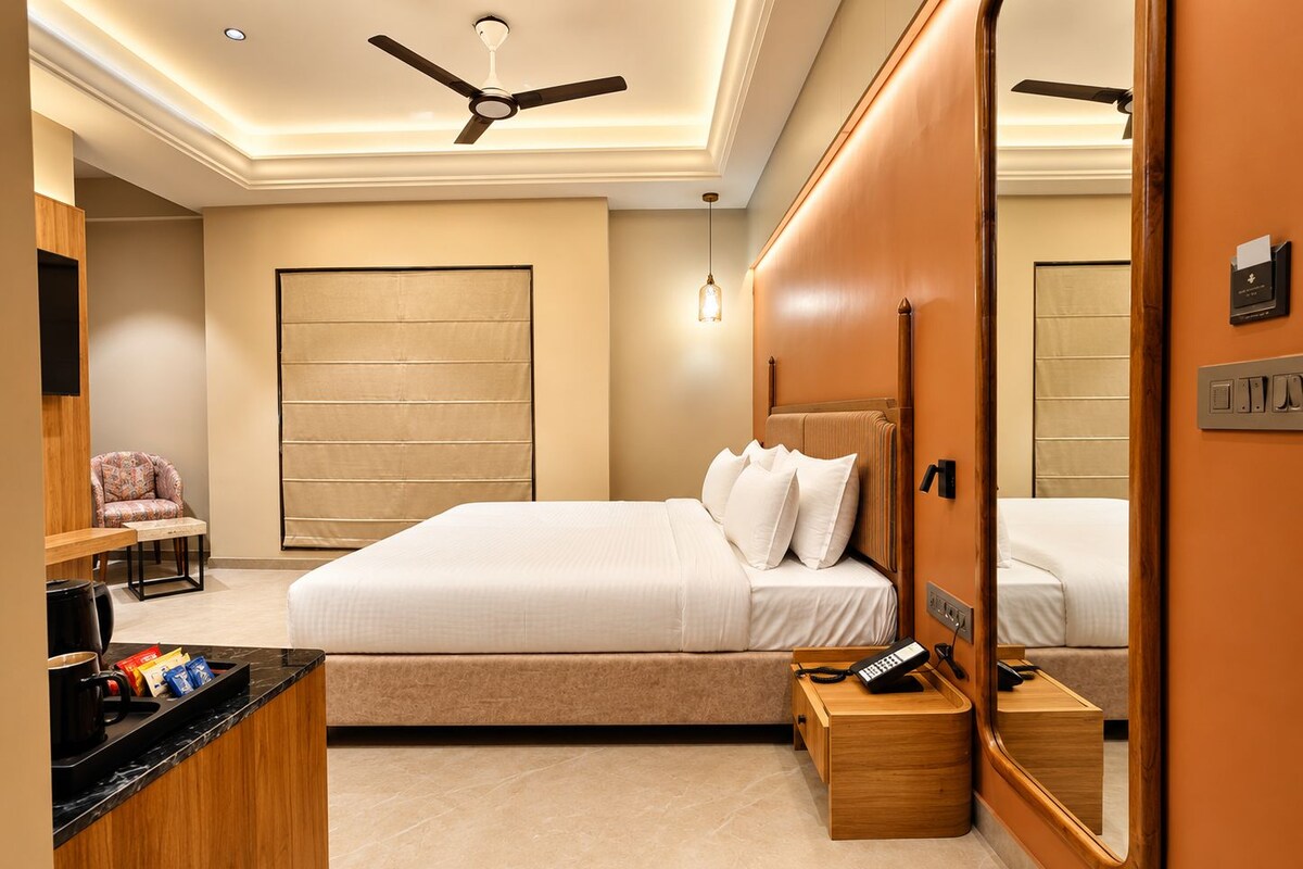 A hotel room with a bed, bedside table, a mirror, a desk with a telephone, and a ceiling fan.