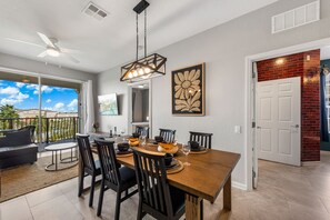 A dining area with a wooden table, black chairs, and a ceiling fan. - Vista Cay 3BR Condo with Resort Pool Balcony (Orlando)