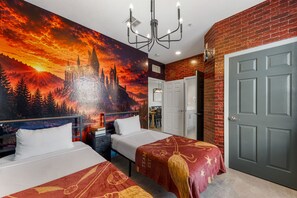 Een hotelkamer met twee bedden, een muurschildering van een kasteel, een kroonluchter en een bakstenen muur.