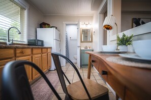 A kitchen with wooden cabinets, a microwave, and a refrigerator. - Cozy Studio • Prime Location • Fast WiFi & Parking (Billings)