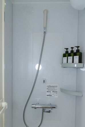 A shower with a handheld showerhead, a wall-mounted control panel, and a shelf with toiletries. - HOTEL GINZA Plus (Imabari-shi Tokiwacho)