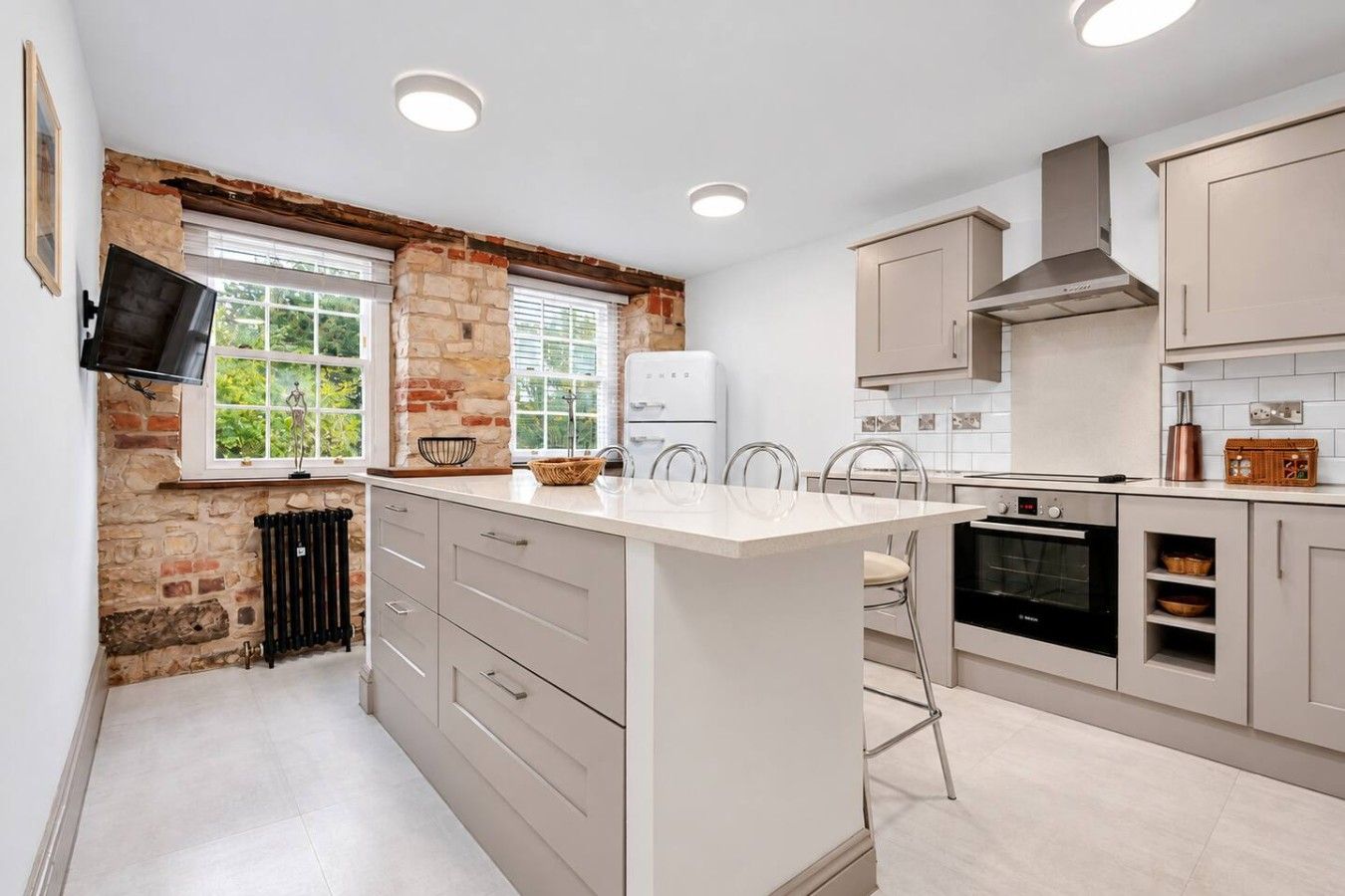 A modern kitchen with a central island, built-in appliances, and a stone accent wall.