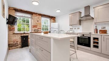 A modern kitchen with a central island, built-in appliances, and a stone accent wall.