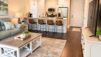 A modern kitchen with white cabinets, a central island with bar stools, and a dining area with a wooden table and chairs.